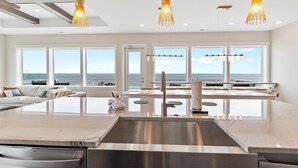 Una cocina moderna con una isla grande, electrodomésticos de acero inoxidable e iluminación colgante.