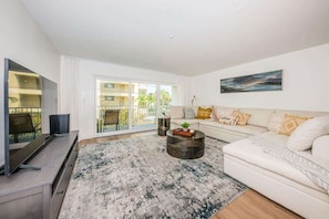 A modern living room with a sofa, coffee table, TV, and a large window.