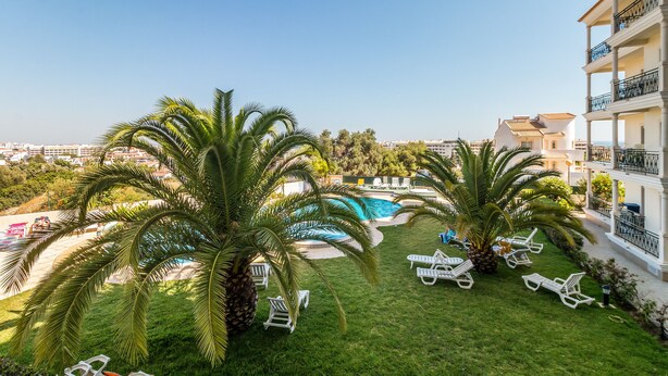 A pool area with palm trees, lounge chairs, and a view of the city. - Superbe Appartement 2 Chambres Avec vue mer (Albufeira)