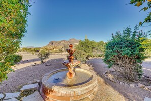 Uma fonte em um jardim, com vista para montanhas ao longe.