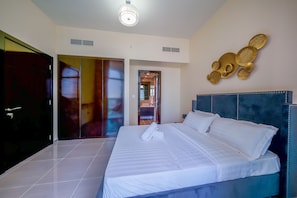 A hotel room with a large bed, a dark headboard, and a wall-mounted decorative piece. - Tanin - Unique Modern Apt with Stunning Canal View (Dubai)