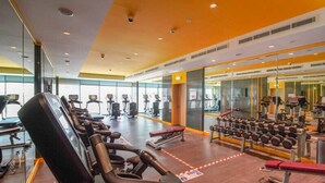 A gym with cardio equipment, weight benches, and dumbbells. - Tanin - Unique Modern Apt with Stunning Canal View (Dubai)