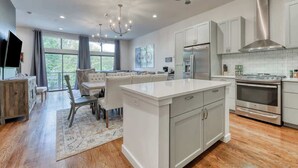 Une cuisine moderne avec des meubles blancs, des appareils en acier inoxydable et un îlot central.