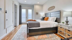 Une chambre à coucher avec un lit, des tables de chevet, un ventilateur de plafond et une vue sur l’extérieur.