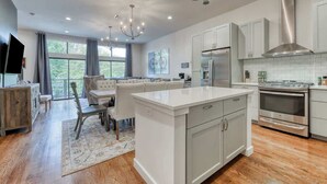 A modern kitchen with white cabinetry, stainless steel appliances, and a large island. - Steps to Pearl - Two Townhomes - Sleeps 22 (San Antonio)