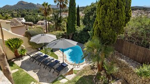 A backyard with a swimming pool, patio furniture, and a stone wall. - Townhouse with pool and mountain views, just 5 minutes from Pollensa downtown  (Pollensa)