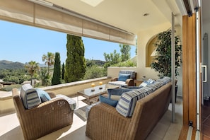 Ein Balkon mit Korbmöbeln, einem Glastisch und Blick auf die Landschaft.
