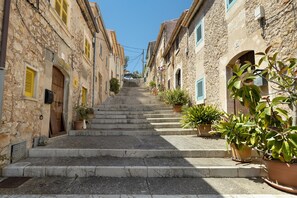 Un escalier en pierre mène à un bâtiment doté d’une porte et de volets en bois.