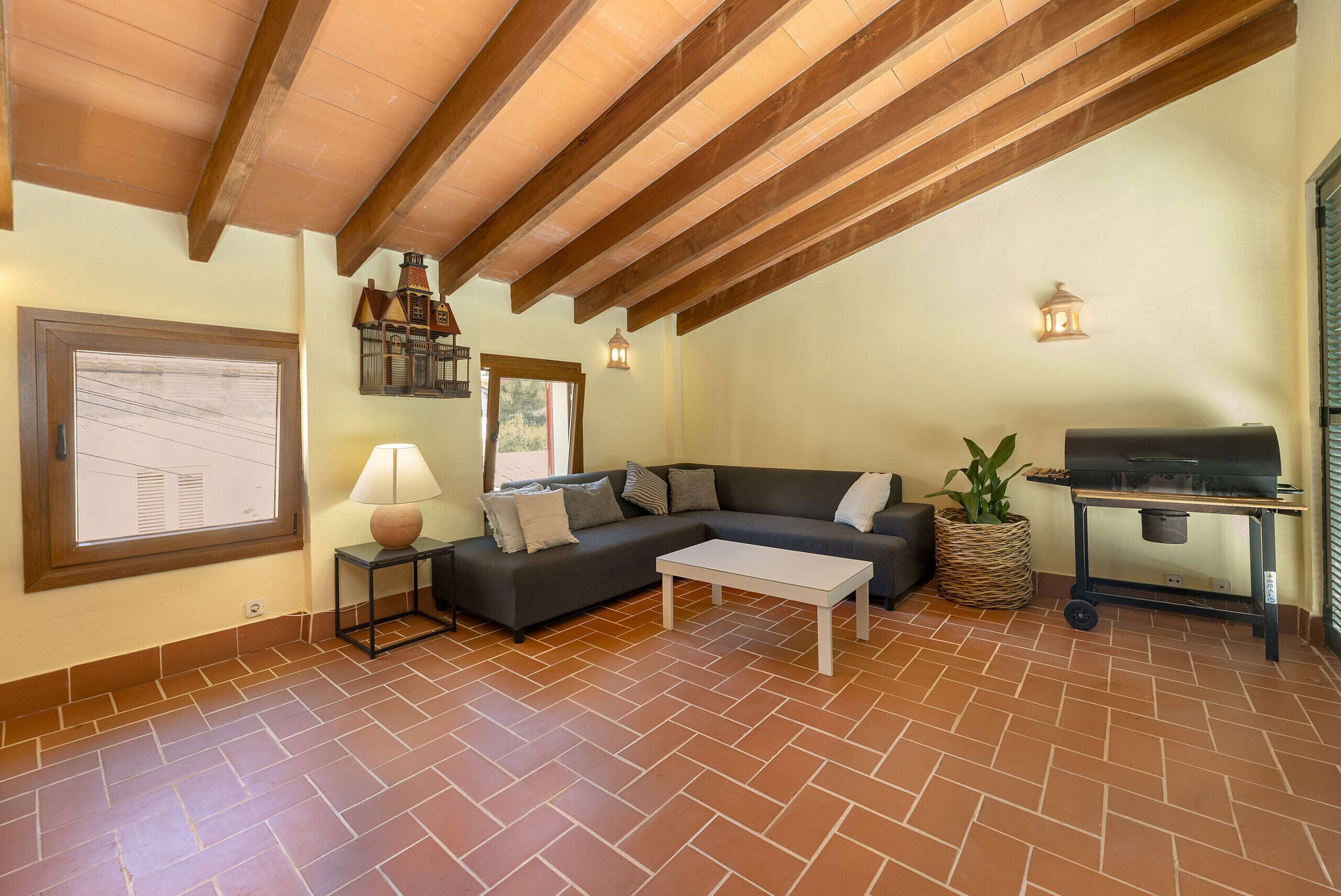 Un salon avec un canapé, une table basse, une lampe, un barbecue et une vue par la fenêtre.