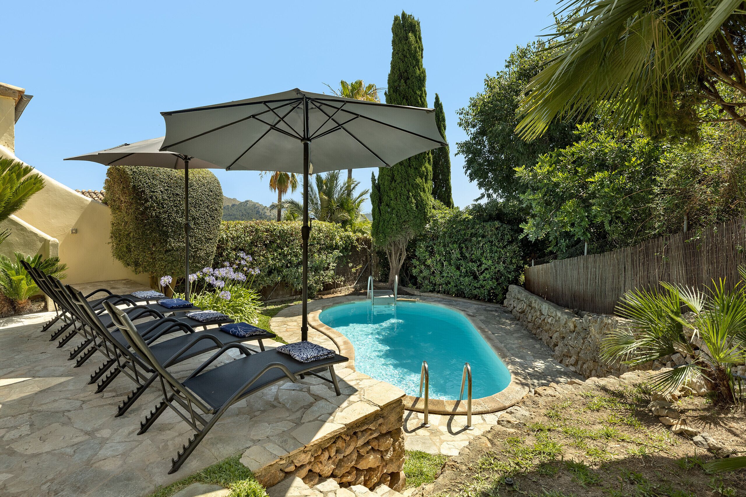 A swimming pool with lounge chairs and an umbrella.