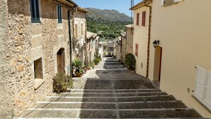 A narrow street with stone buildings, a staircase, and a mountain in the background. - Townhouse with pool and mountain views, just 5 minutes from Pollensa downtown  (Pollensa)