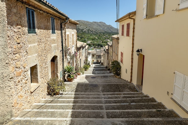 Eine enge Straße mit Steinhäusern, einer Treppe und einem Berg im Hintergrund.