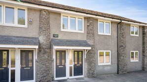 A two-story building with stone pillars, a grey facade, and a tiled roof. - Kentmere Haven with Parking by LetMeStay (Kendal)