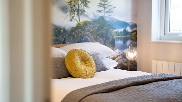 A bedroom with a bed, pillows, a bedside lamp, and a mural of a mountain landscape. - Kentmere Haven with Parking by LetMeStay (Kendal)