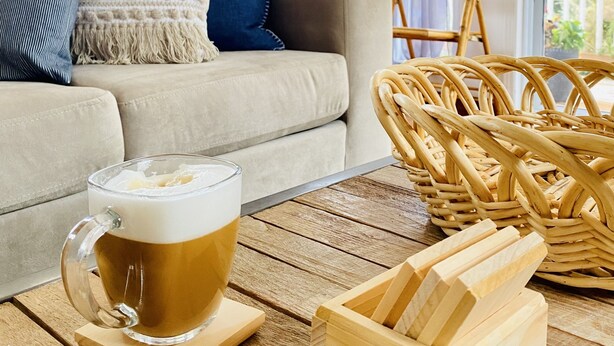 A cozy living room with a sofa, a wicker chair, a wooden coffee table, and a glass mug of coffee. - Lakehouse w/ stunning views and a swimming pool‼️ (Val-des-Bois)