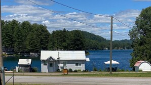 A swimming pool with a person swimming, surrounded by a grassy area and a house with a dock. - Lakehouse w/ stunning views and a swimming pool‼️ (Val-des-Bois)