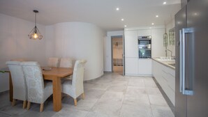 A modern kitchen with white cabinets, a built-in oven, and a stainless steel refrigerator.
