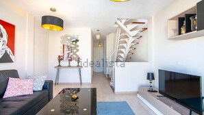 Un salon moderne comprenant un canapé, une table basse, un téléviseur et un escalier menant à un autre niveau.