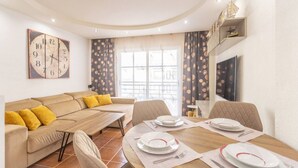 Una sala de estar moderna con un sofá, una mesa de comedor lista para cuatro personas y un gran reloj de pared.