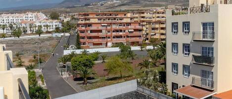 A residential building with multiple balconies, a swimming pool, and a view of the surrounding landscape.