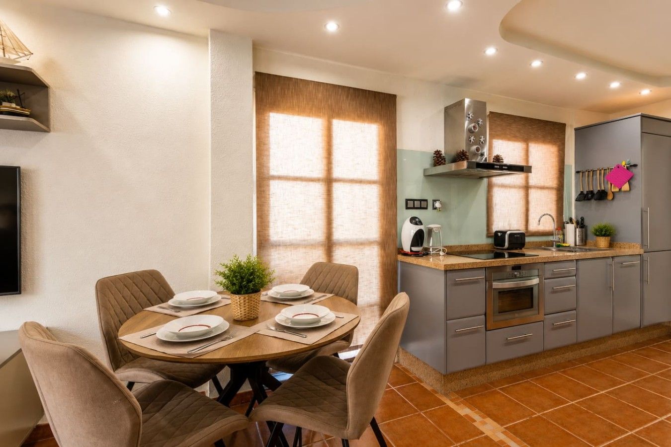 Una cocina moderna con armarios grises, horno integrado y cafetera.