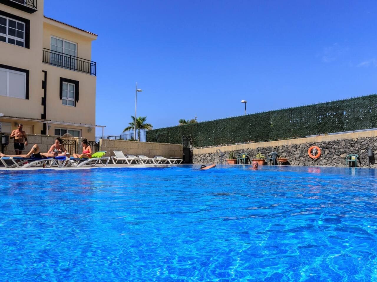 Una piscina amb gandules i un bou salvavides a la paret.