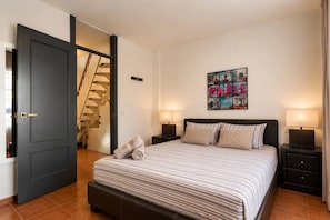 Ein Schlafzimmer mit einem Bett, zwei Nachttischen, einem Wandbild und einer Treppe.
