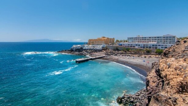 Un hotel frente al mar con costa rocosa, un muelle y una playa.