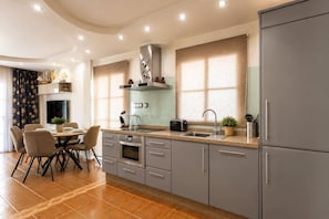 Eine moderne Küche mit grauen Schränken, einem eingebauten Backofen und einem Essbereich mit Tisch und Stühlen.