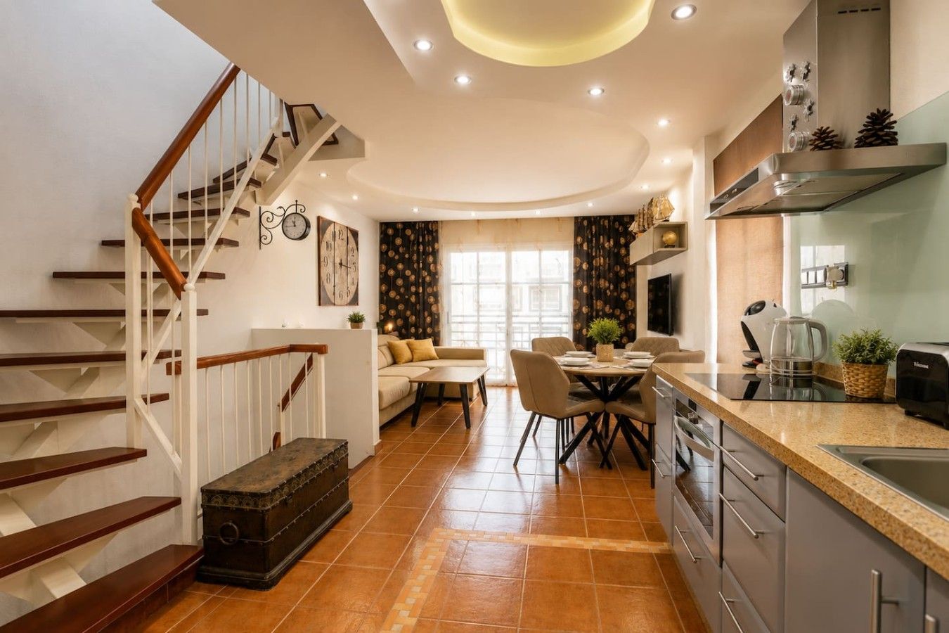 Una cocina moderna con comedor, una escalera y una sala de estar.