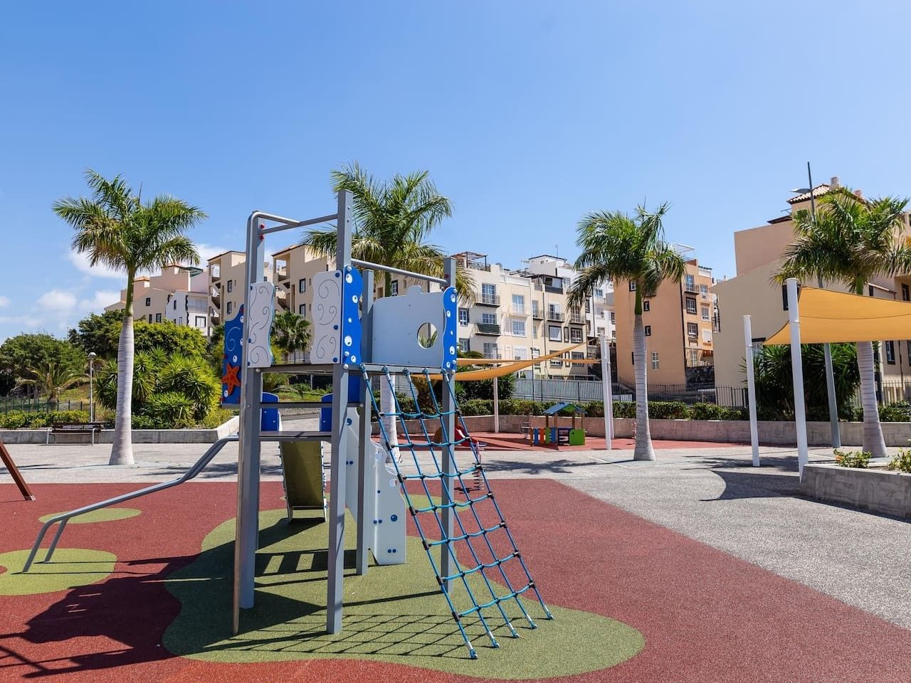 Un parque infantil con estructuras para escalar y una zona de juegos en rojo y verde.