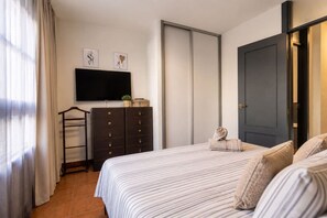 Ein Schlafzimmer mit einem Bett, einem Schminktisch, einem Fernseher und einer Tür.