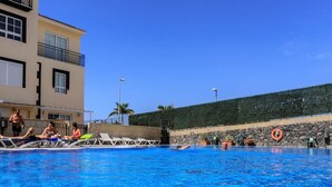 Una piscina con sillas de descanso y un flotador en la pared.