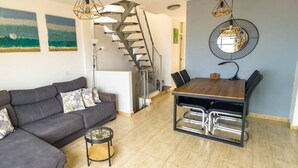 Un salon moderne avec un canapé gris, une table à manger avec des chaises et un escalier en colimaçon.