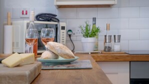 Un comptoir de cuisine avec une assiette de pain, une bouteille de vin et un verre de vin rosé.