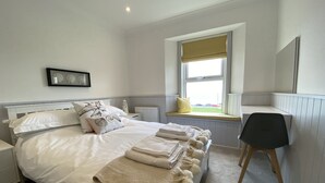Una camera da letto con un grande letto, una panca-finestra, una scrivania e una sedia.