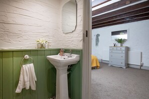 A bathroom with a white sink, green walls, and a wooden ceiling.