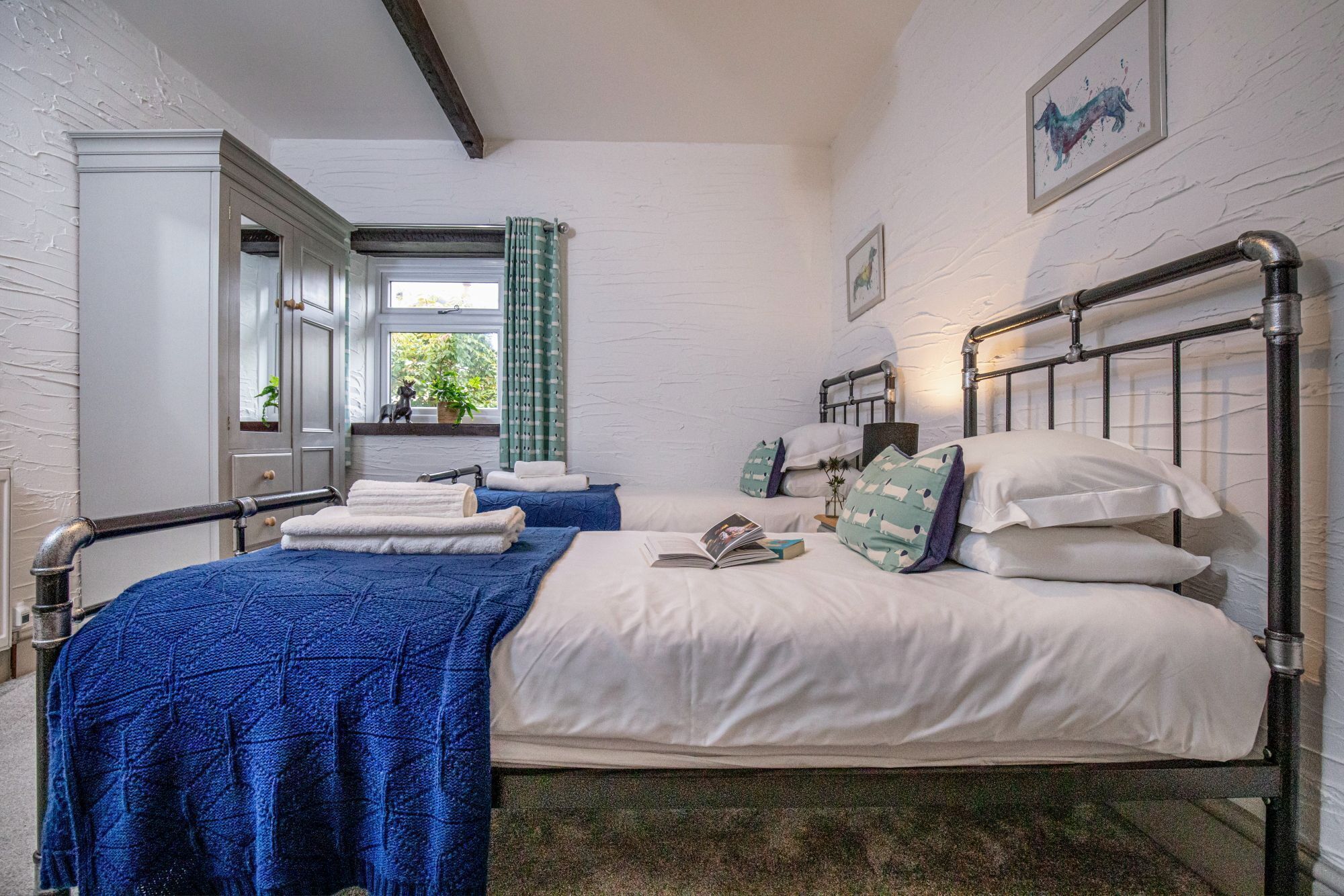 Une chambre à coucher avec un lit, une fenêtre avec des rideaux, un miroir et une plante.