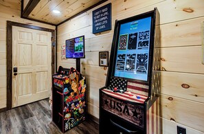 Een houten interieur met speelautomaten, een deur en een bord aan de muur.