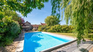 A rectangular swimming pool with a clear blue water surface, surrounded by a stone deck and lush greenery. - School House, Burnham Thorpe, Norfolk (Burnham Thorpe)
