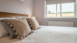 Quarto com uma cama grande, janela com vista para um campo e radiador.