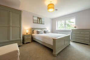 A bedroom with a bed, nightstands, a dresser, and a window.