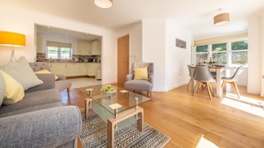 Un salon moderne comprenant un canapé, une table basse en verre et un coin repas avec des chaises et une table.