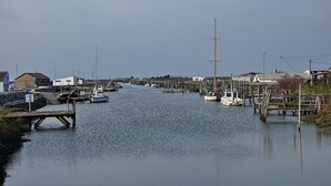 Een jachthaven met aan de kade afgemeerde boten, houten steigers en gebouwen op de achtergrond.