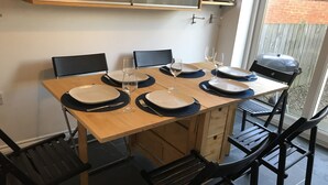 Mesa de comedor para cuatro personas con sillas negras, una mesa de madera y un aparador de vidrio arriba.