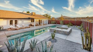 Une maison moderne dotée d’une piscine, de chaises longues et d’un jardin planté de cactus.