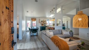Un salon moderne avec un grand canapé, un coin repas et une cuisine en arrière-plan.