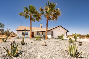 A house with a white exterior, a garage, and a gravel driveway.