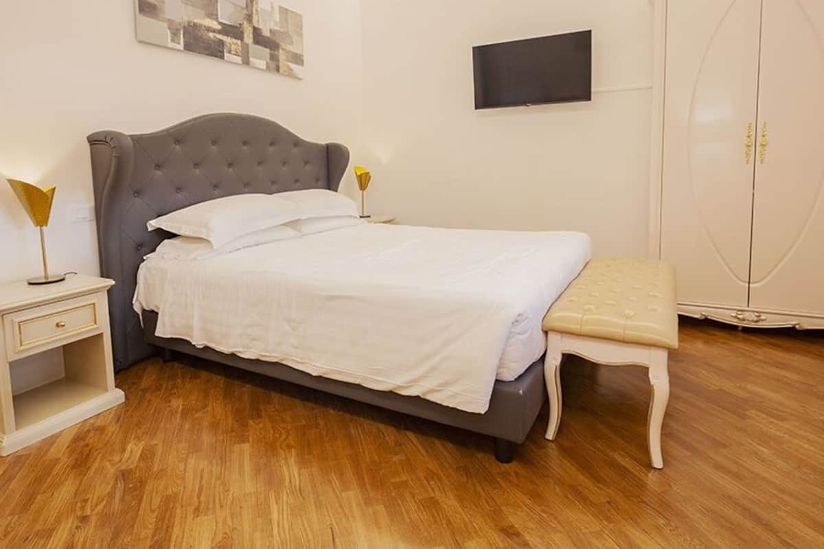 A neatly arranged bedroom with a bed, bedside table, lamp, and a wardrobe.