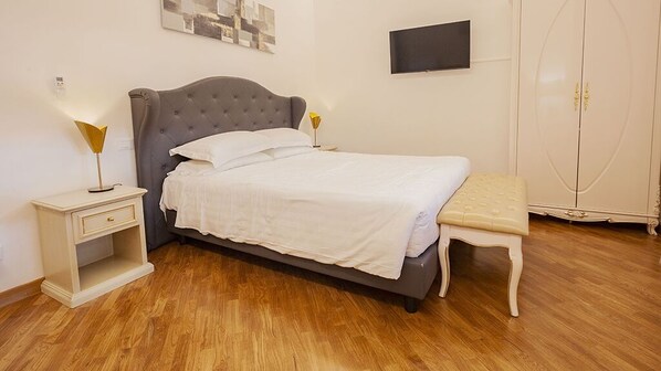 Un dormitorio ordenado con cama, mesita de noche, lámpara y armario.